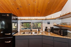 Una cocina moderna con un refrigerador negro, un lavamanos de acero inoxidable y un microondas.