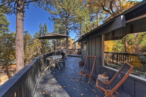 An outdoor deck with a table and chairs, surrounded by trees.