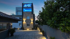 A modern building with a neon sign reading "La Vie" and a paved courtyard with potted plants.