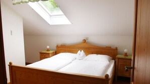 Une chambre à coucher avec un lit en bois, deux tables de chevet, une commode et un puits de lumière.