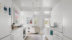 Een moderne keuken met witte kasten, een centraal eiland en een kamerkleed met patroon.