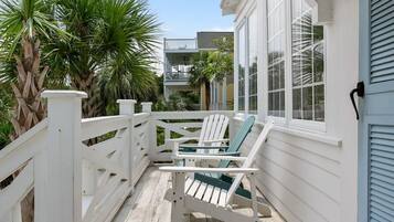 A wooden deck with a white railing, a white chair, and a table.