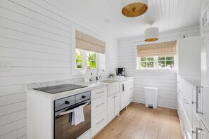 A modern kitchen with white cabinetry, a marble countertop, and a built-in oven.