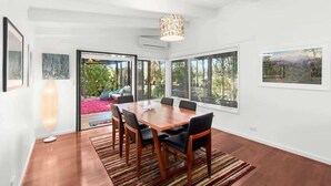 A dining area with a wooden table, chairs, and a patterned rug.