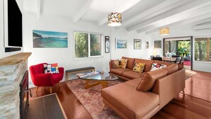 A spacious living room with a large brown sofa, a red armchair, and a stone fireplace.