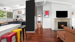 A modern kitchen with a black column, a fireplace, and a TV.