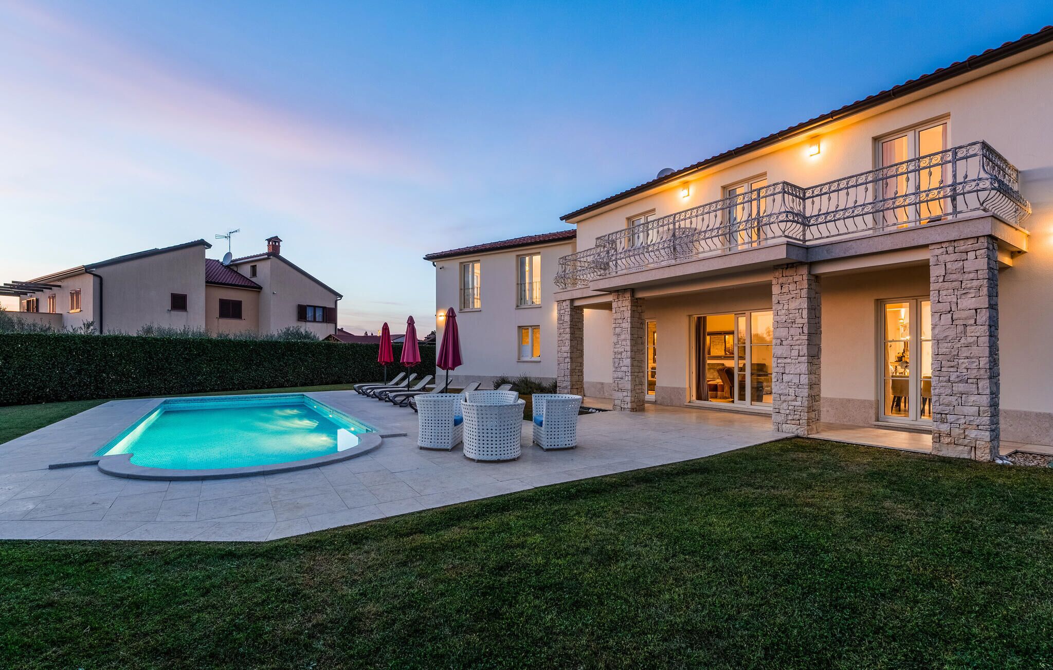 A modern house with a swimming pool, outdoor seating, and a stone facade.