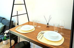 A dining area set for two, complete with table, chairs, and a potted plant.