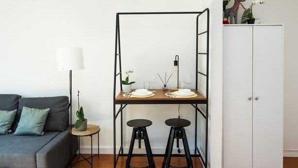 A modern living space with a sofa, a dining table with stools, a lamp, and a cabinet. - Charming 2-bed Apartment in London (London)