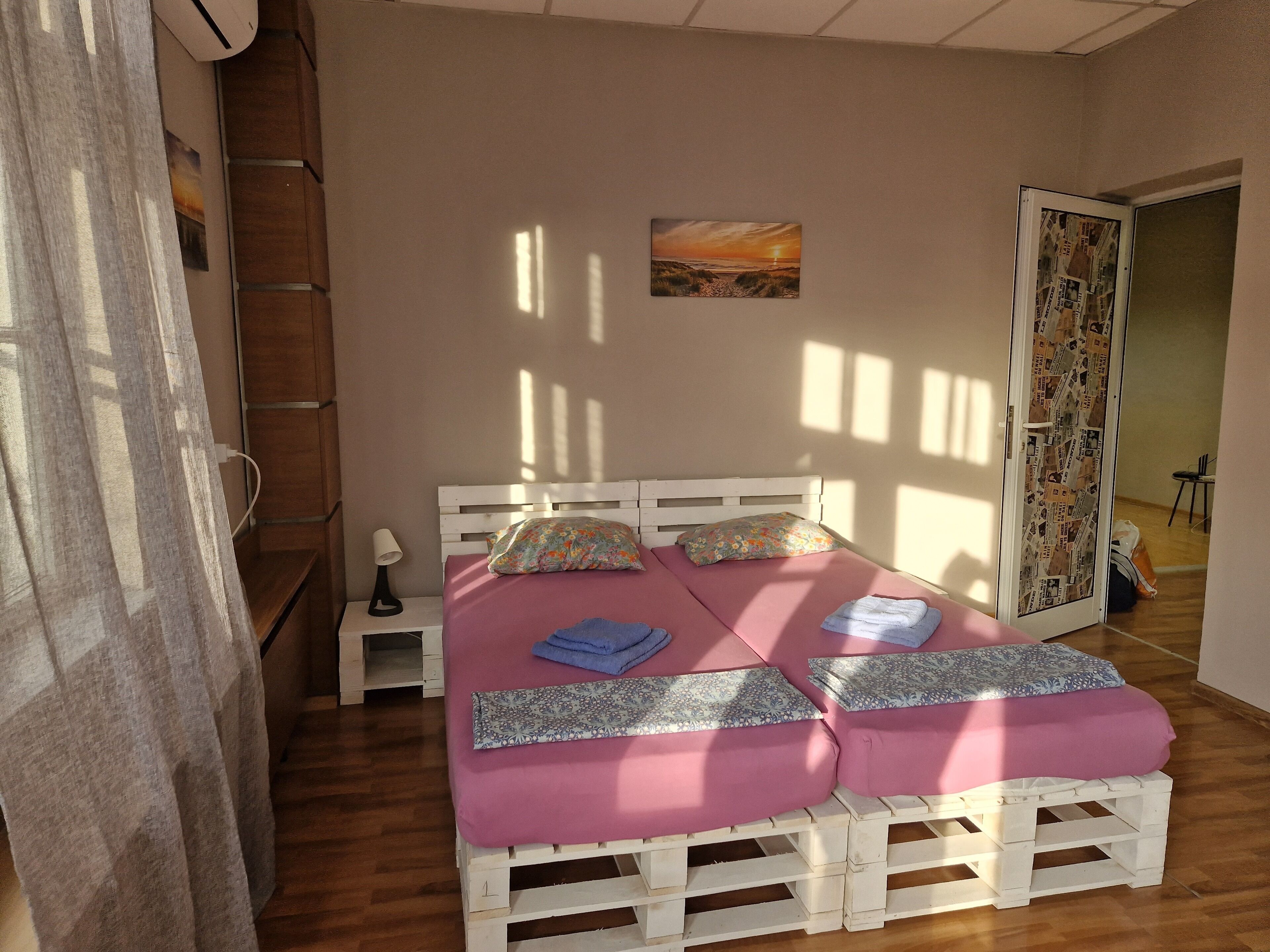 A bedroom with a wooden bed, a nightstand, a lamp, and a painting on the wall.