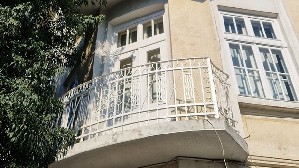A multi-story building with a curved balcony and a tree in the foreground. - Lambo's Corner  (Varna)