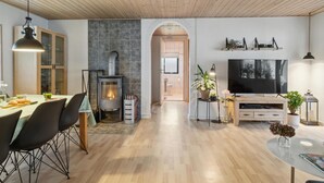 Een moderne woonkamer met een open haard, een eethoek en een televisie.