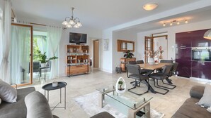 Una sala de estar moderna con televisor, sofá, mesa de centro y comedor con sillas y una mesa.