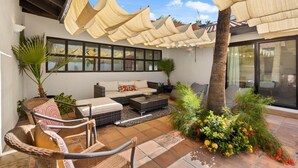 A covered patio area with a sofa, chairs, and a dining table. - Mountain Views, Heated Pool and Spa (Palm Springs)
