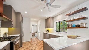 A modern kitchen with a central island, built-in appliances, and a view of a green outdoor area. - Mountain Views, Heated Pool and Spa (Palm Springs)