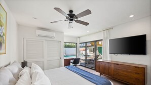 A bedroom with a bed, a ceiling fan, a TV, a dresser, and a view of an outdoor pool. - Mountain Views, Heated Pool and Spa (Palm Springs)