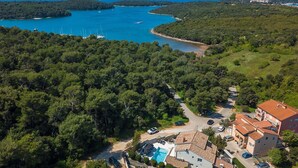 An aerial view of a coastal area with dense forest, a swimming pool, and a building with a tiled roof. - Stunning home in Pula (Pula)