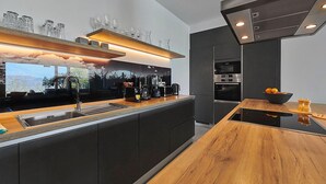 A modern kitchen with a wooden countertop, a built-in oven, and a coffee station. - Villa Sauvignon (Motovun)