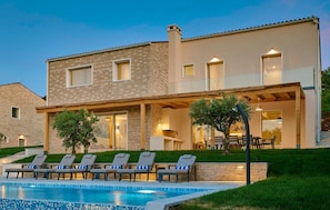 Une maison moderne à deux étages, dotée d’une piscine, d’un espace salon extérieur et d’une pelouse bien entretenue.