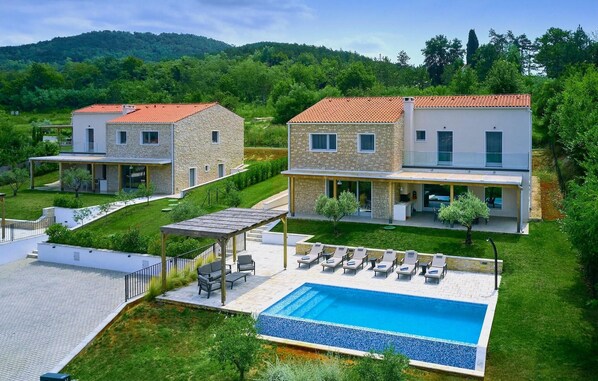 Une villa moderne dotée d’une piscine, d’un espace salon extérieur et d’un jardin.