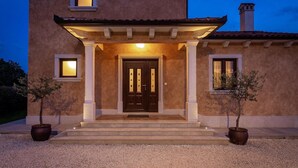 A two-story house with a dark brown door, a covered porch, and two potted trees. - Amazing home in Porec (Porec)