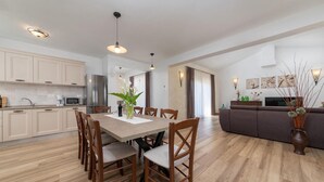 A modern kitchen with a dining area, wooden chairs, a table, and a sofa. - Amazing home in Porec (Porec)
