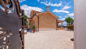 A courtyard with a building featuring a beige facade and a tiled roof, surrounded by gravel. - Amazing home in Porec (Porec)