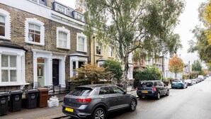A row of terraced houses with a parked car on the street. - Sunshine Joy, by Veeve (London)