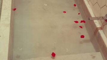 A bathtub with water and rose petals.
