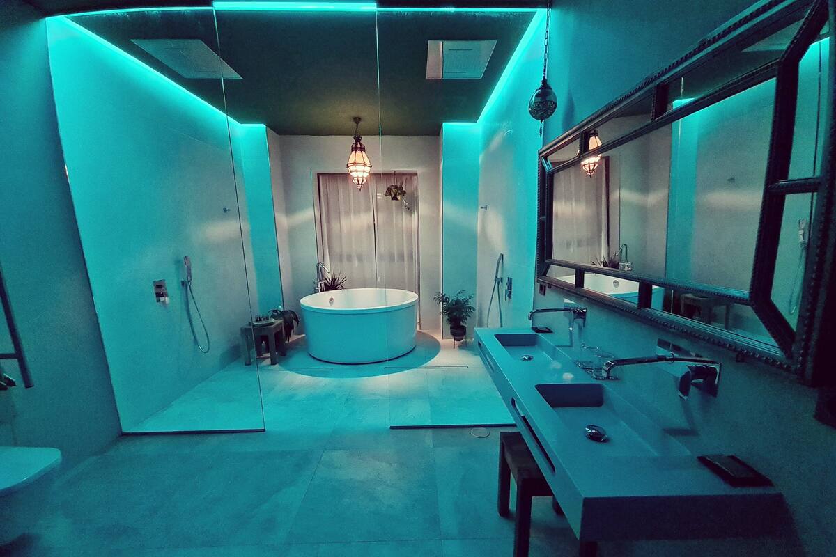 Un baño moderno con una bañera grande, un tocador con espejo y una lámpara colgante.