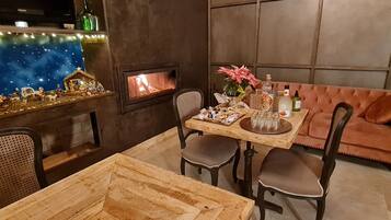 Un coin repas chaleureux avec une table en bois, quatre chaises, un canapé rose, une cheminée et une crèche de Noël accrochée au mur.