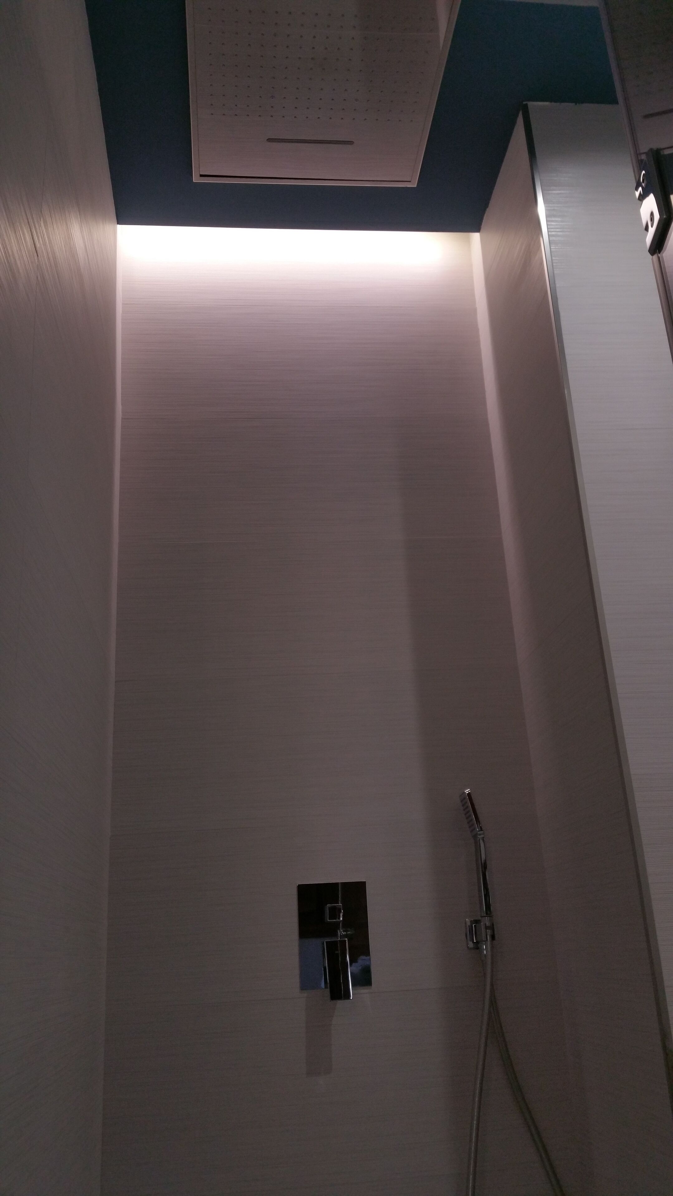 A shower area with a control panel and a handheld showerhead.