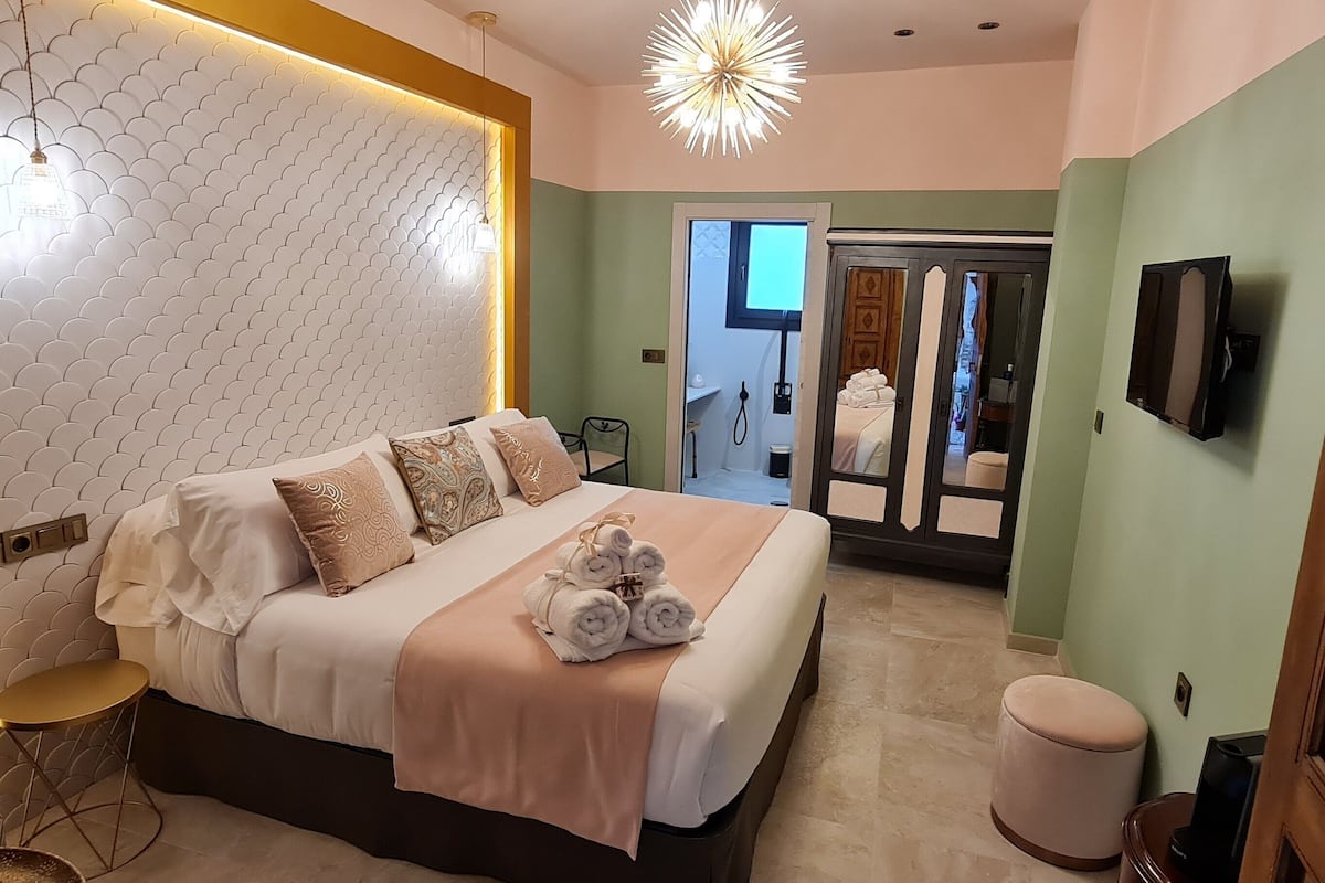 Una habitación de hotel moderna con una cama grande, una mesa redonda y un televisor.