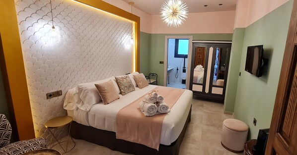 A modern hotel room with a large bed, a round table, and a television. - Murallas de Jayran Hotel Boutique (Almeria)
