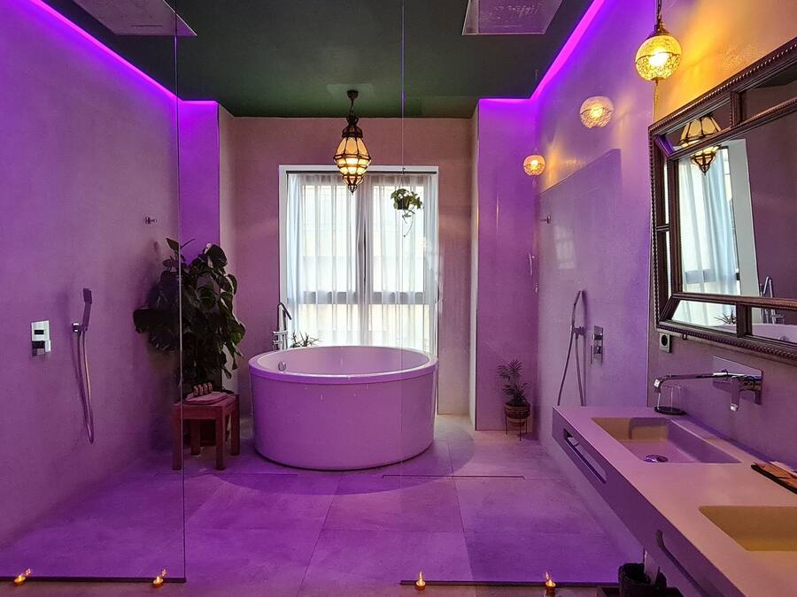 A modern bathroom with a large bathtub, a vanity with a mirror, and a hanging light fixture.