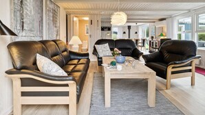 A modern living room with leather sofas, a wooden coffee table, and a hanging light fixture.