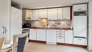 A modern kitchen with white cabinets, a wooden countertop, and a dining area with a table and chairs.