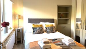A neatly arranged hotel room with a bed, bedside table, lamp, and a wardrobe. - 4 Bed House Sleeps 7 - Parking, Garden, Wifi (Killarney)
