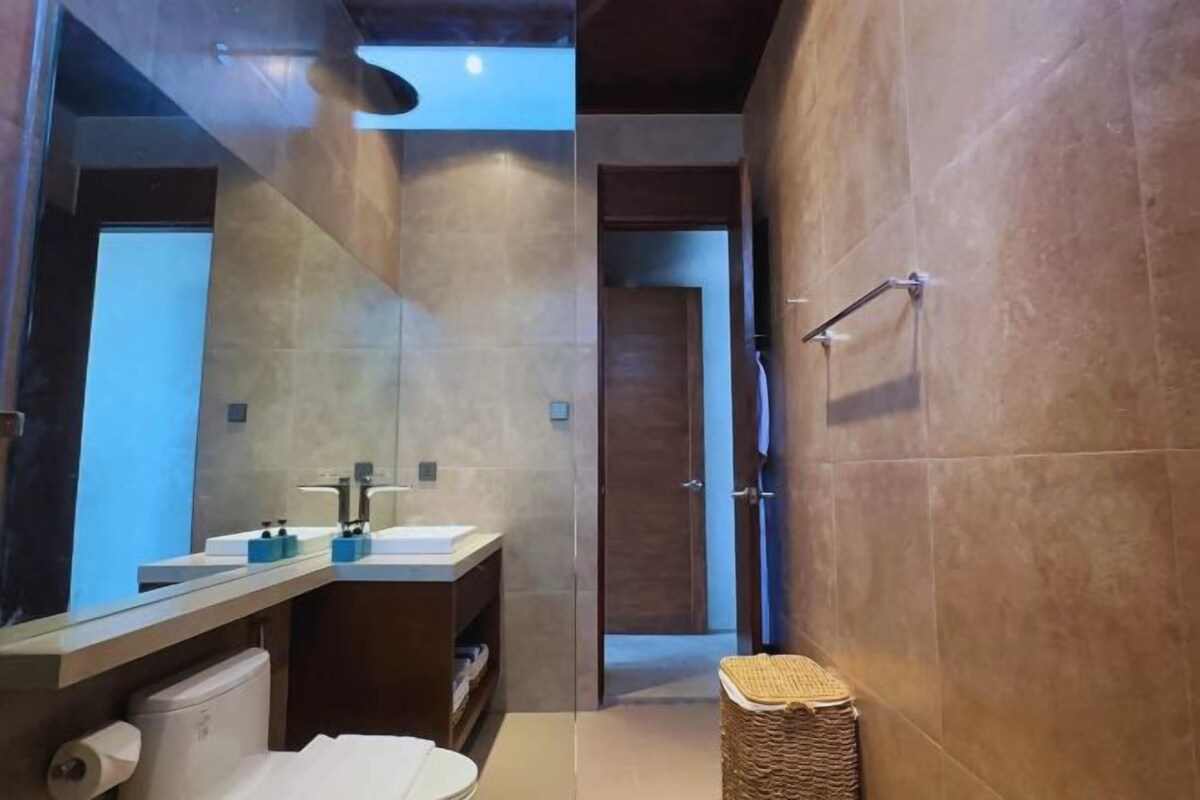 A modern bathroom with a large mirror, a sink, and a toilet.
