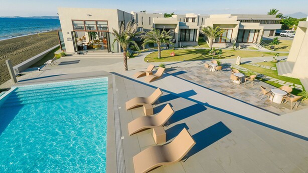 A modern hotel with a pool, lounge chairs, and a view of the beach. - TANA Beach Villas (Lian)