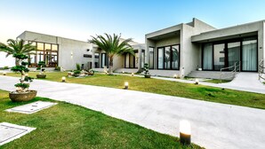 A modern building with large windows, a well-maintained lawn, and outdoor lighting. - TANA Beach Villas (Lian)