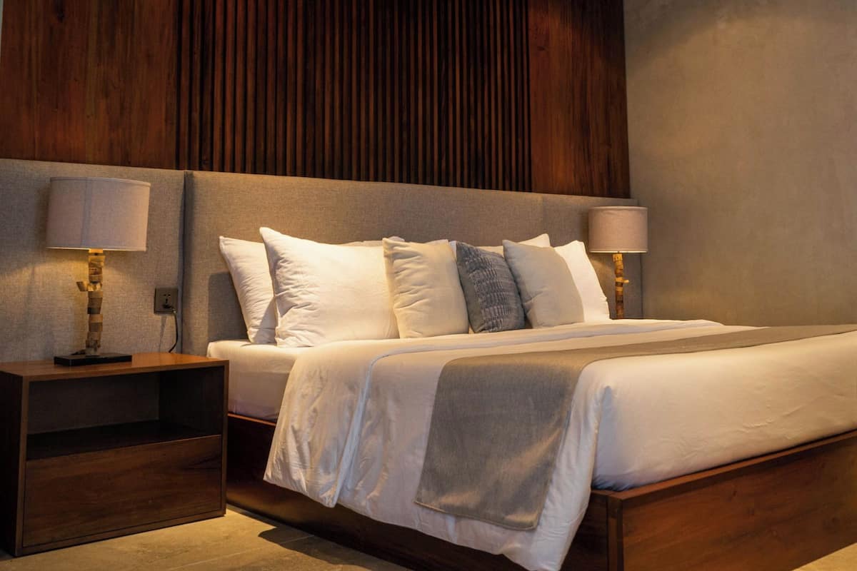 A neatly arranged bedroom with a large bed, two bedside tables, and a wooden headboard.