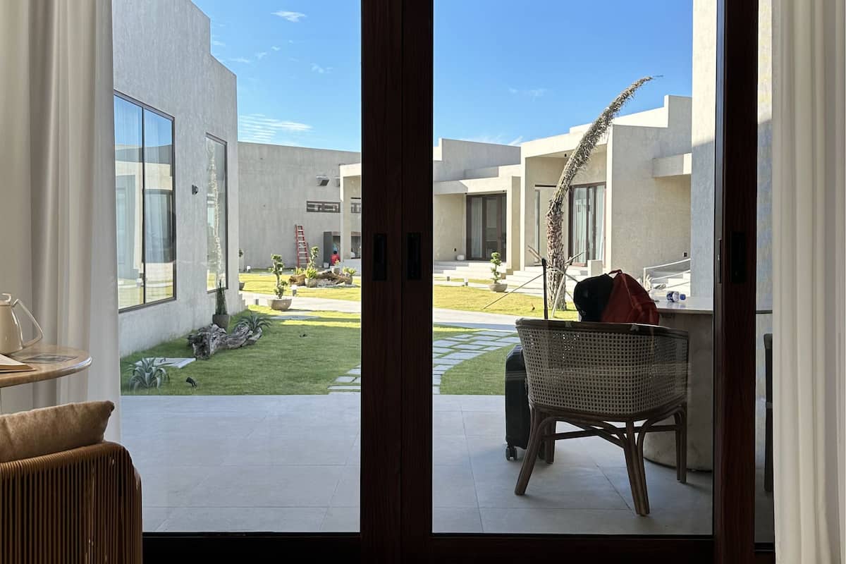 A modern hotel room with a sliding glass door leading to a courtyard.