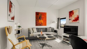 A modern living room with a grey sofa, a round coffee table, a TV, and artwork on the walls. - Nice apartment in Fanø with WiFi (Fanø)