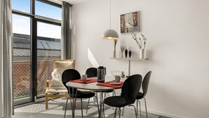 A modern dining area with a round table, black chairs, a coffee maker, and a pendant light. - Nice apartment in Fanø with WiFi (Fanø)