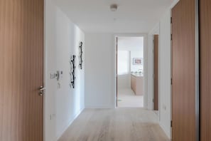 A hallway with wooden doors, a light switch, and a power outlet on the wall.