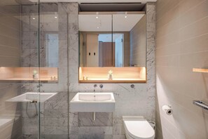 A modern bathroom with a glass-enclosed shower, two sinks, a toilet, and a wooden shelf with toiletries. - Soho 2-Bed Penthouse · AC · Sleeps 6 (Greater London)