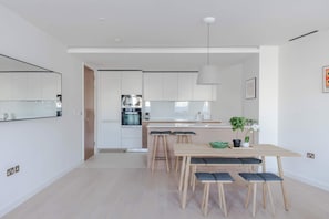 Una cocina moderna con armarios blancos, una isla central y taburetes de bar.