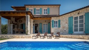 A two-story stone building with a swimming pool, outdoor seating, and a covered patio area. - Awesome home in Porec (Porec)