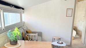 Un coin repas accueillant avec une table et des chaises en bois, une plante en pot et une petite table ronde sur laquelle est posée une bougie.